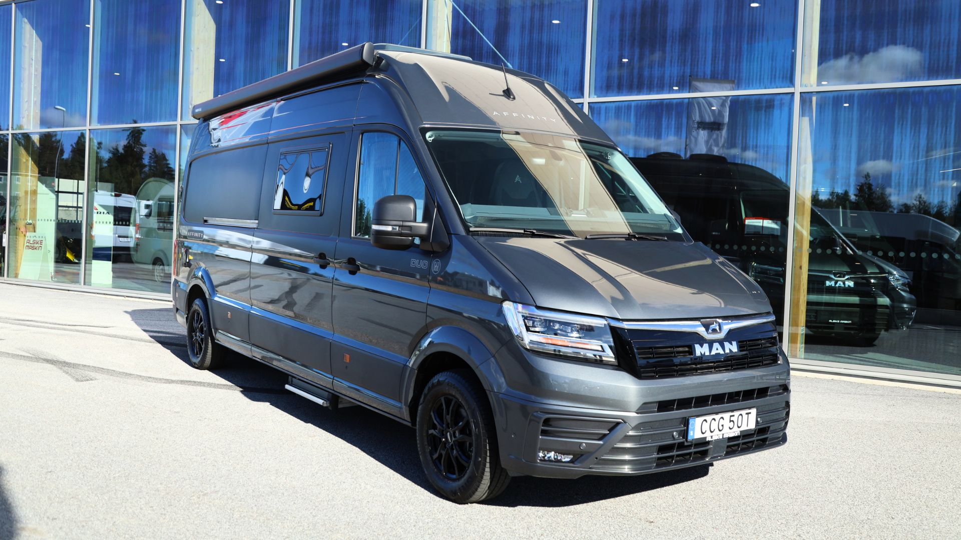 Campervan i landskap med berg, personer vilar utanför i kvällsljus